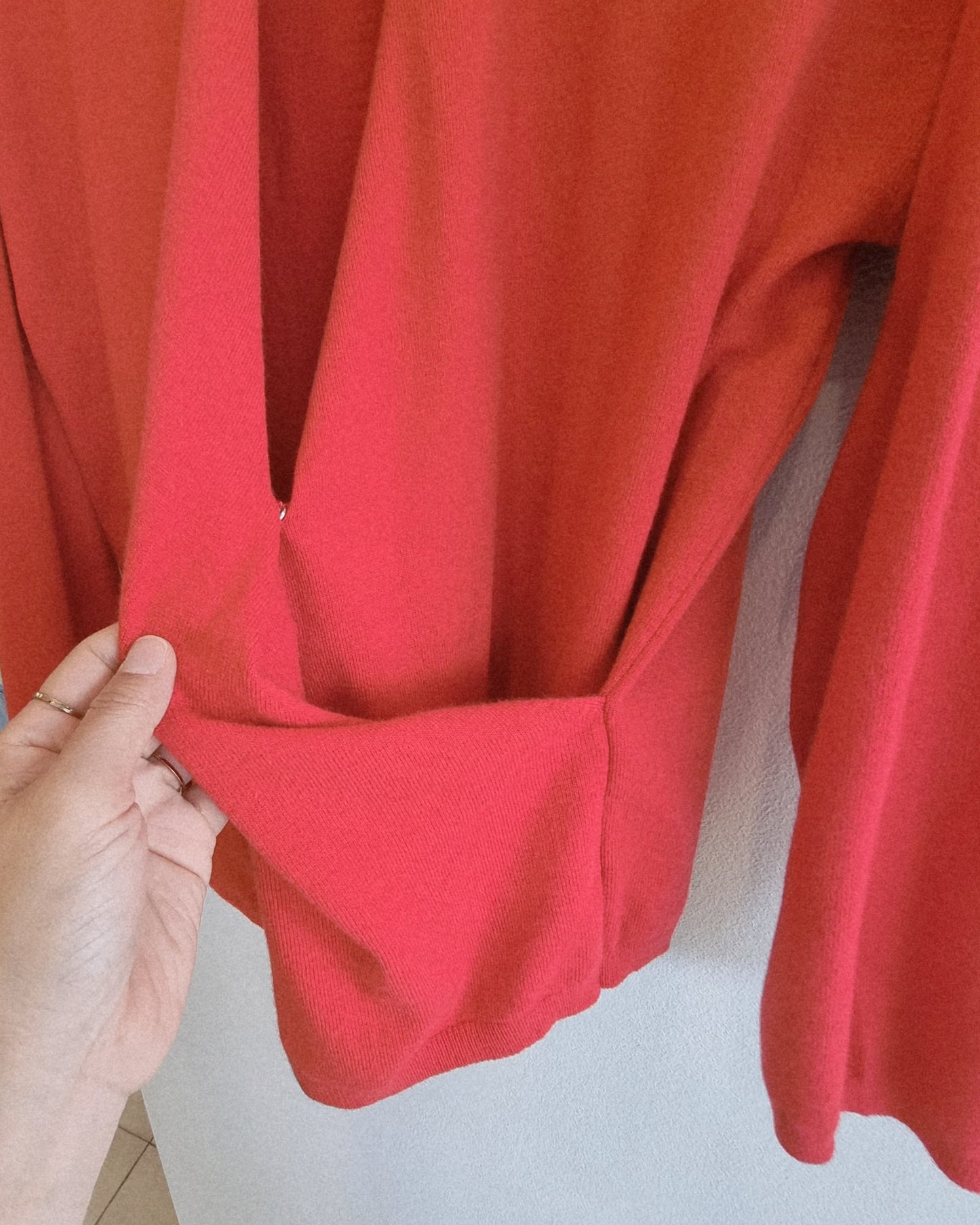 Red wrap knit top hanging on hanger, product only