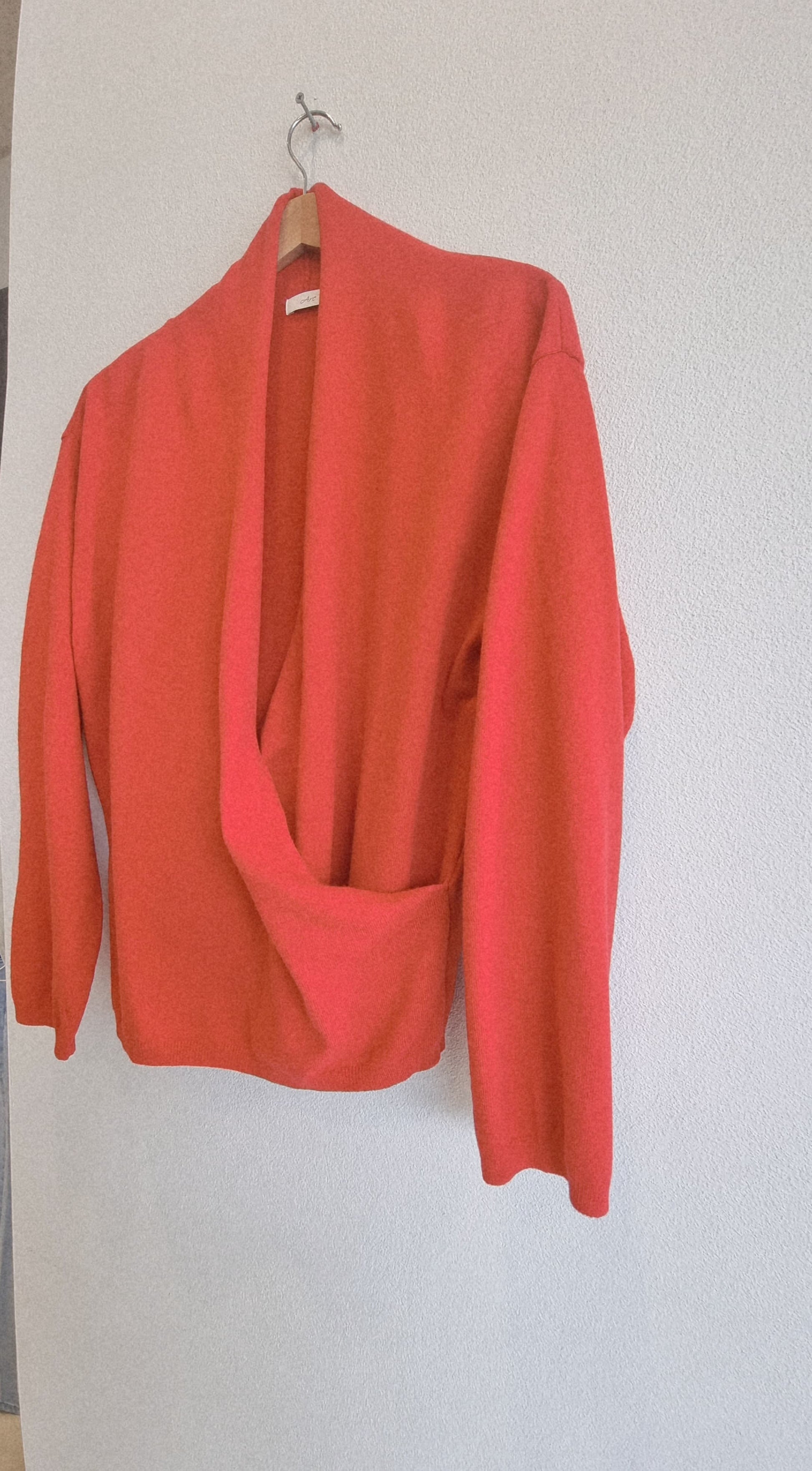Close-up detail of red wrap knit hanging on hanger, fabric and wrap design