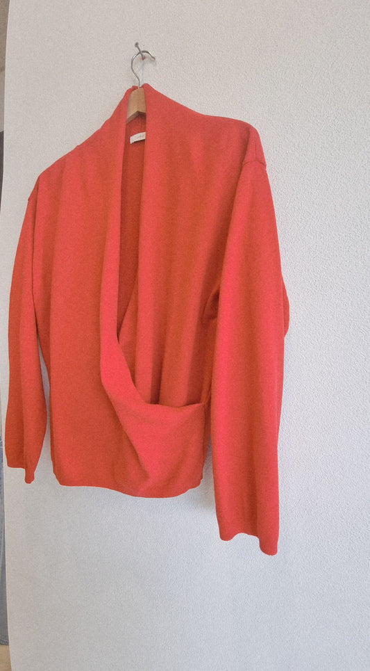 Close-up detail of red wrap knit hanging on hanger, fabric and wrap design
