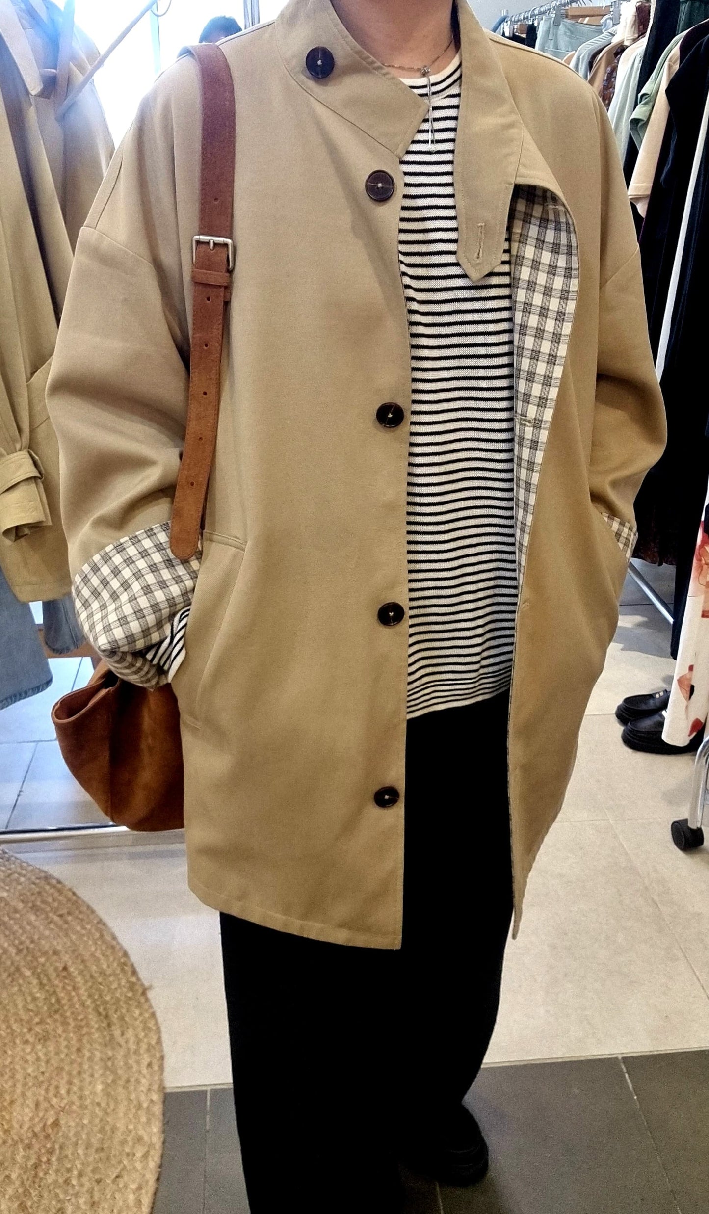 Model wearing Beige reversible trench coat with strait black pants, front view
