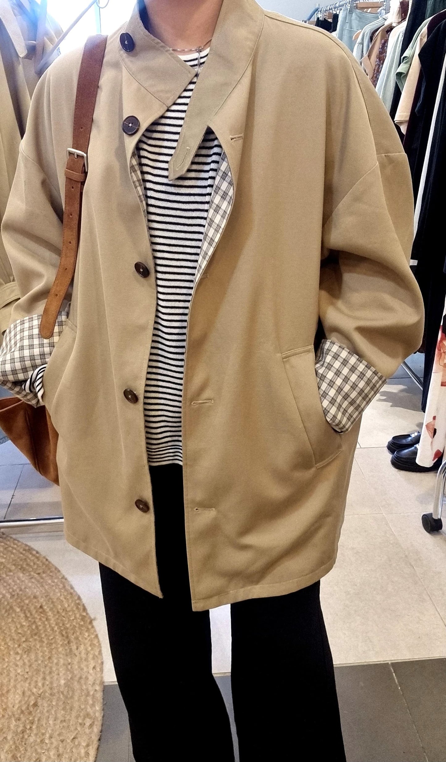 Front view of beige reversible trench coat worn with check pattern.