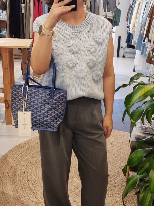 Model wearing blue daisy flower knit vest front view with Goyad bag