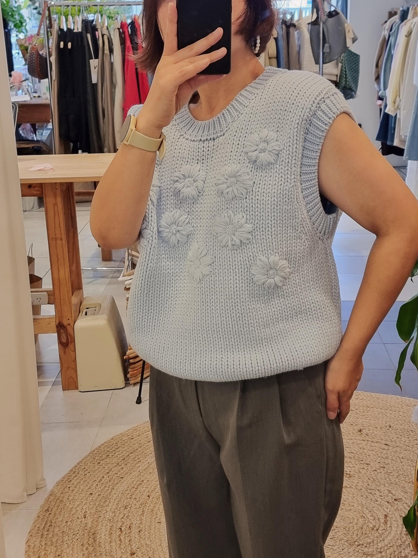 Model wearing blue daisy flower knit vest side view