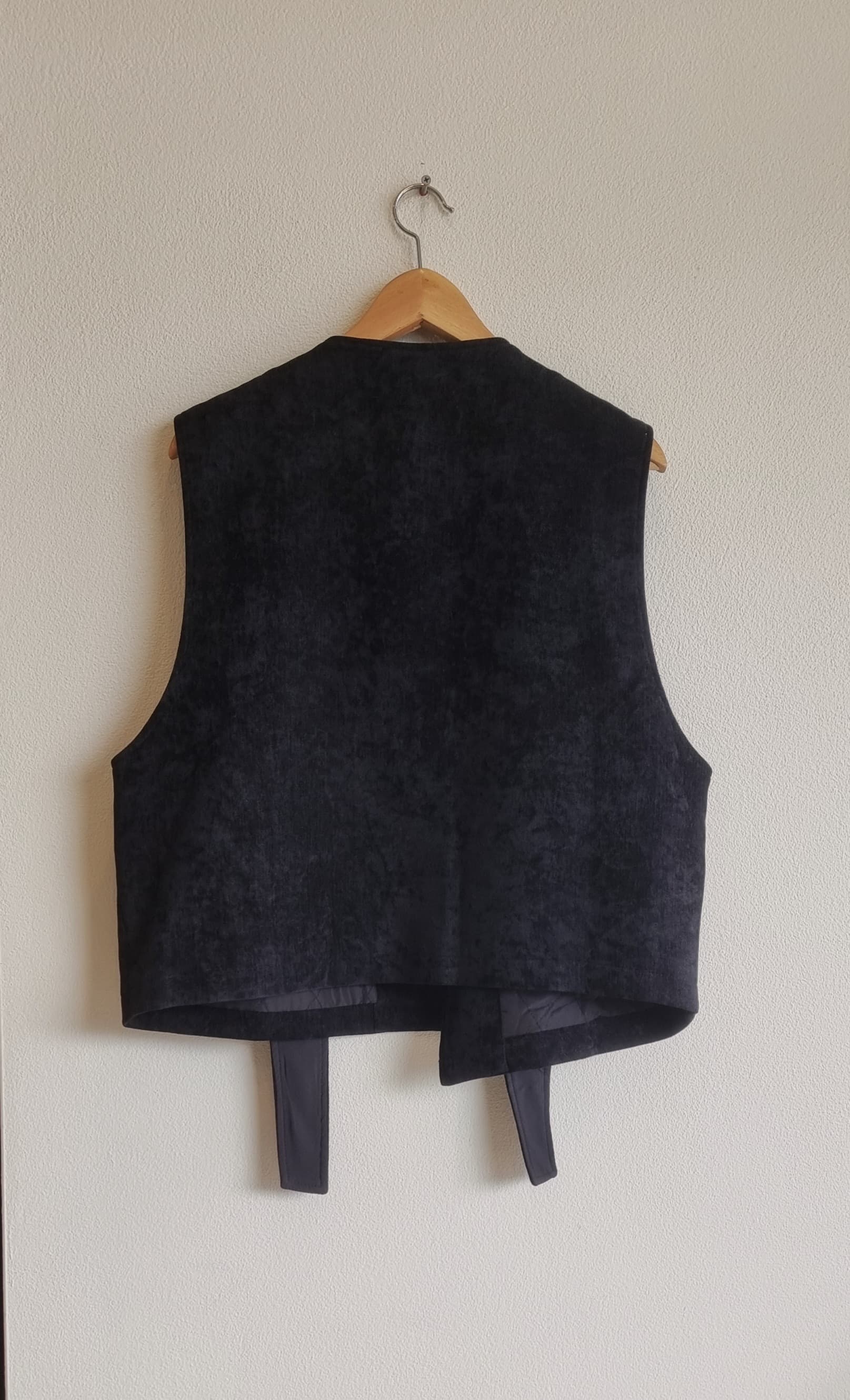Black corduroy vest back view on hanger showing structure and fit