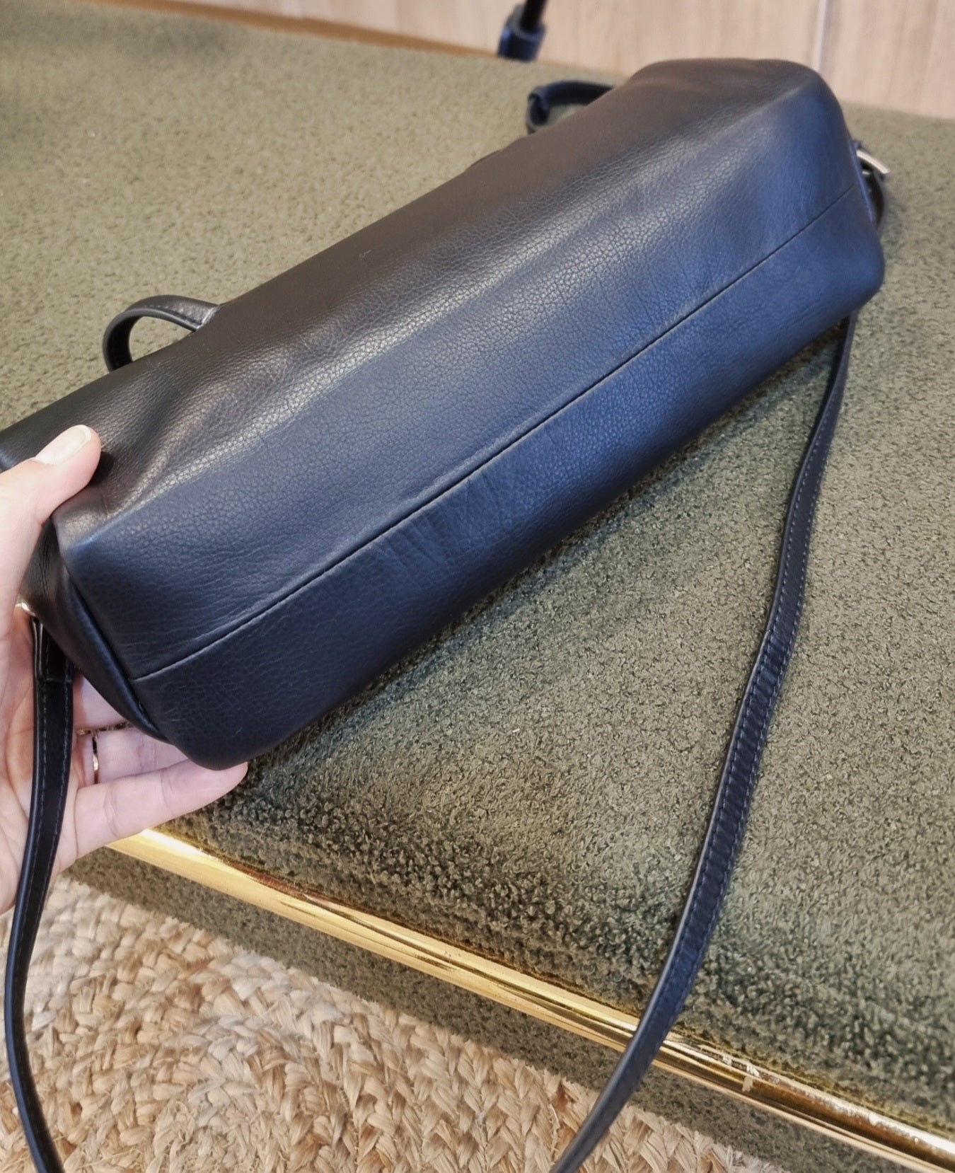 black leather cylinder bag side view on surface