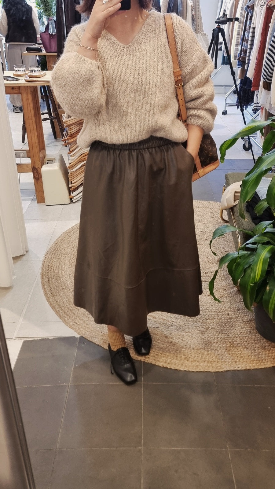 Brown faux leather A-line skirt styled with a soft knit sweater