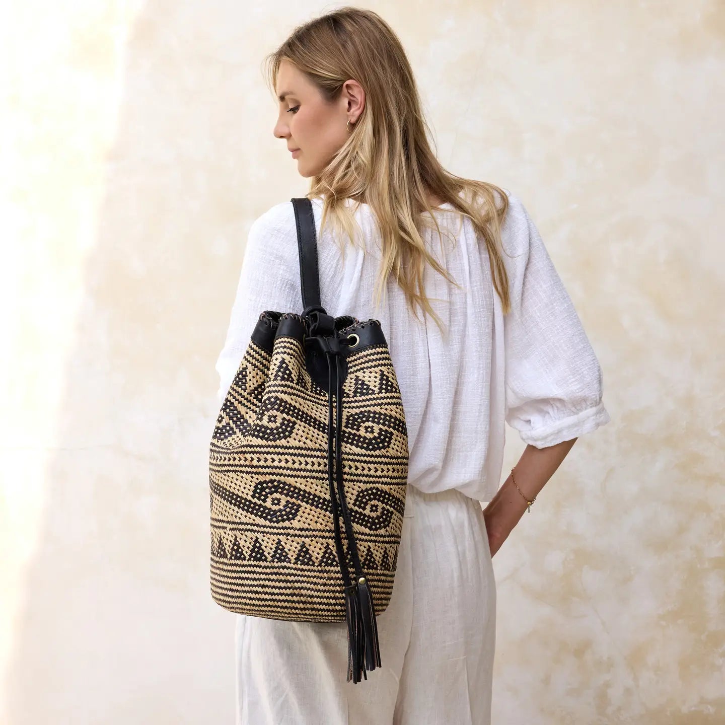Side-back view of a model wearing a handwoven Borneo rattan shoulder bag with leather trim.