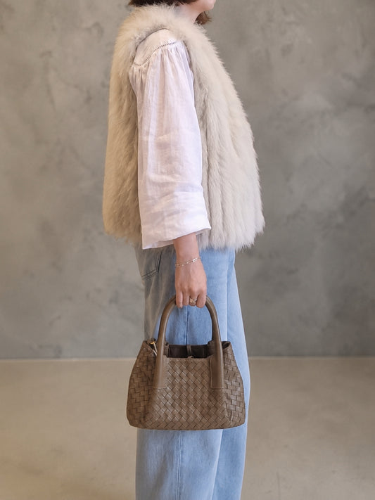 Side view of brown woven leather handbag with detachable strap
