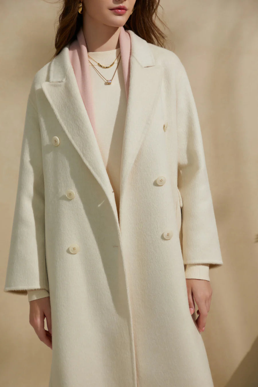 Woman wearing a cream merino wool coat with double-breasted design, front view