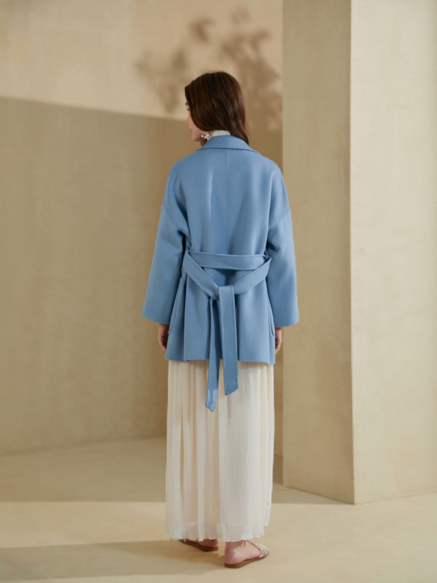 “Back view of a light blue belted blazer paired with a flowy ivory skirt, showcasing the relaxed fit and waist-tie detail.”