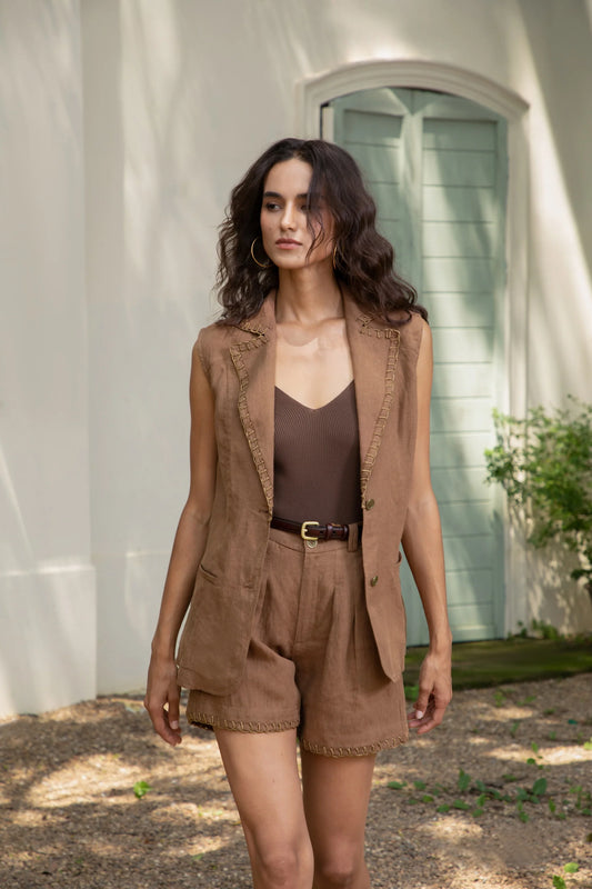 “Woman wearing a brown linen vest and matching shorts set in an outdoor setting.”