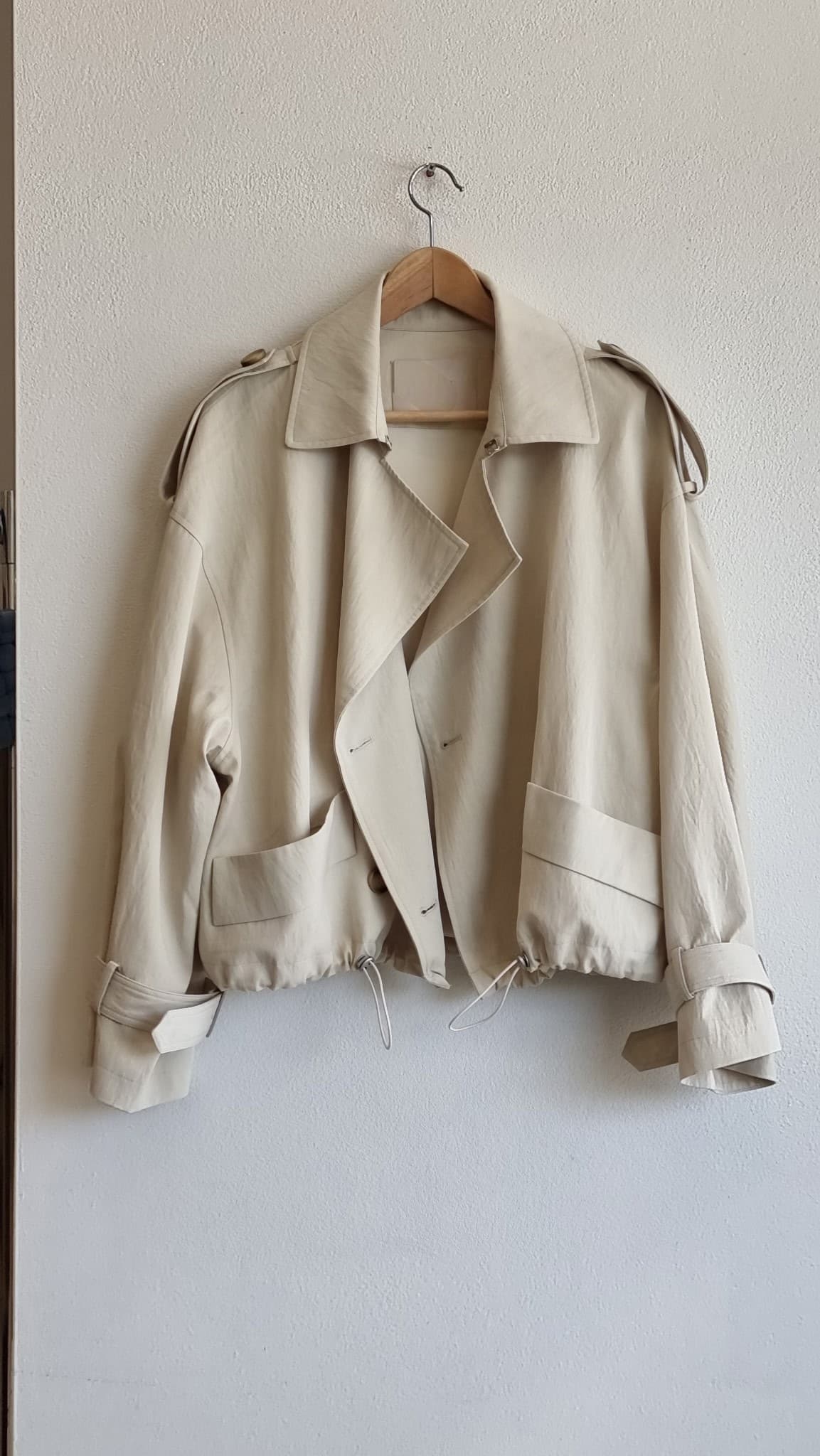 Cream Breeze Short Trench hanging on a rack, product only