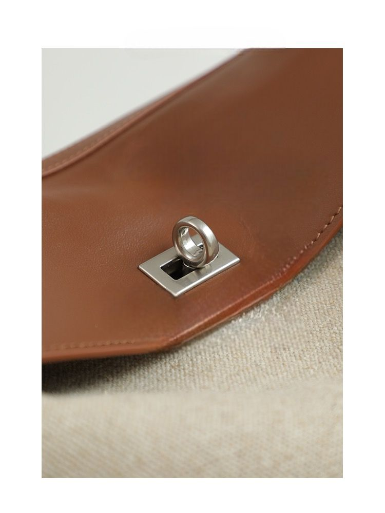 Close-up of silver clasp on brown leather flap of canvas bag