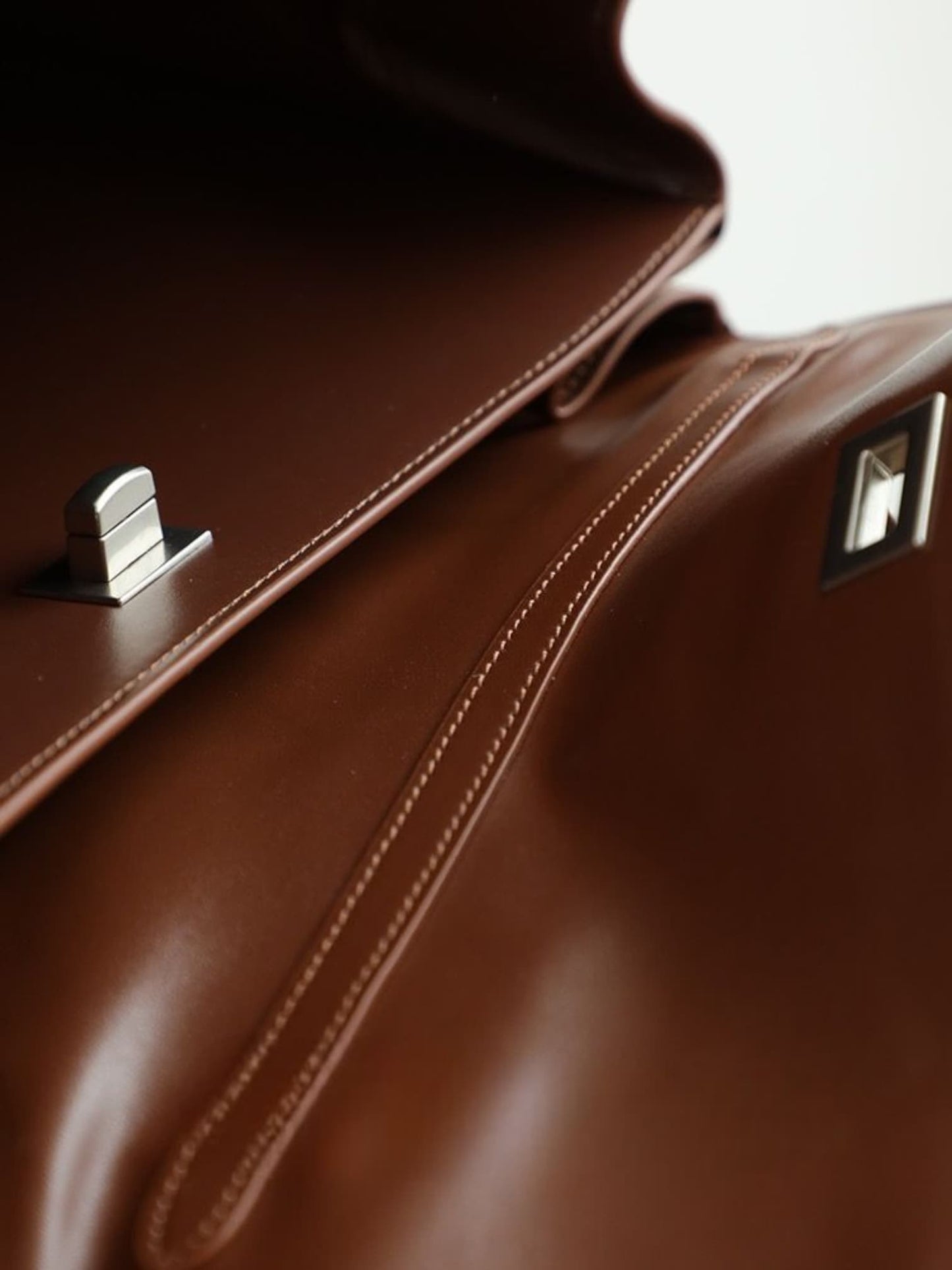 Close-up of leather flap and metallic closure on canvas bag
