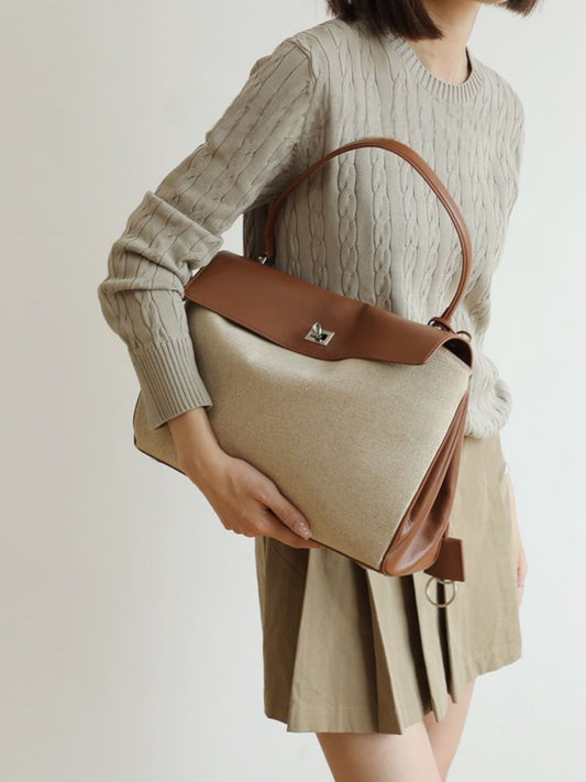 Model holding beige canvas bag with leather handle – front view