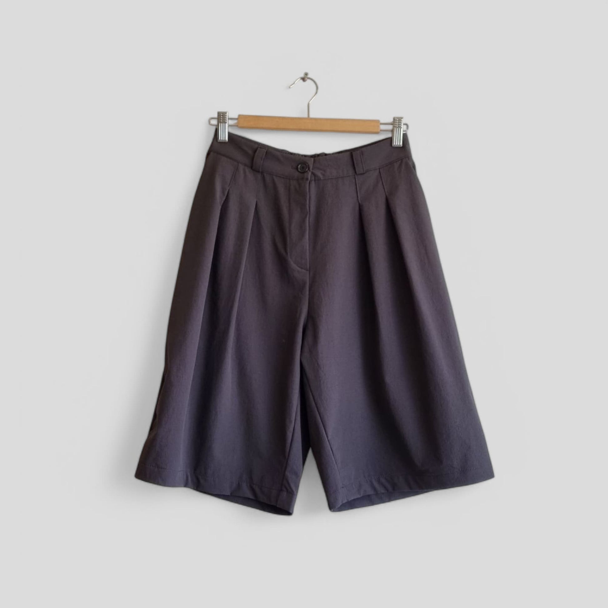 Dark wide-leg pants hanging on a wooden hanger – front view