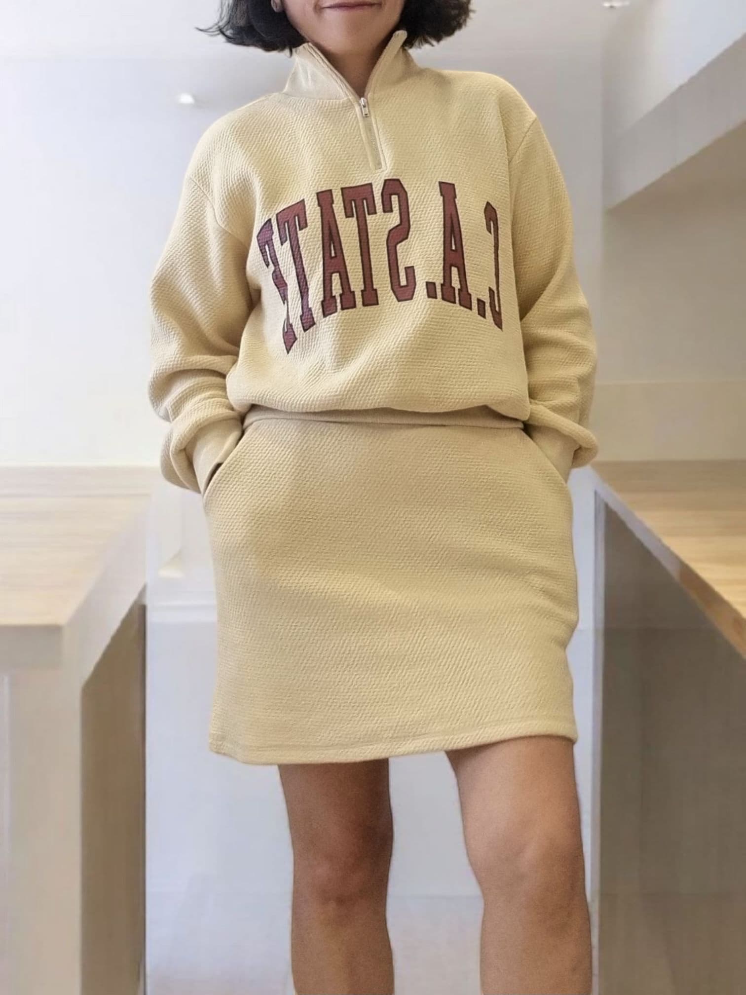 Model wearing beige zip-up sweatshirt – cropped front view