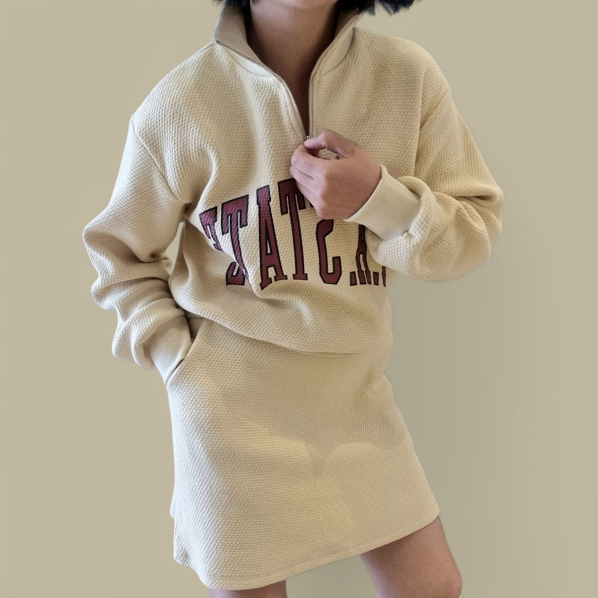 "Beige textured hoodie top and matching skirt set modeled indoors"