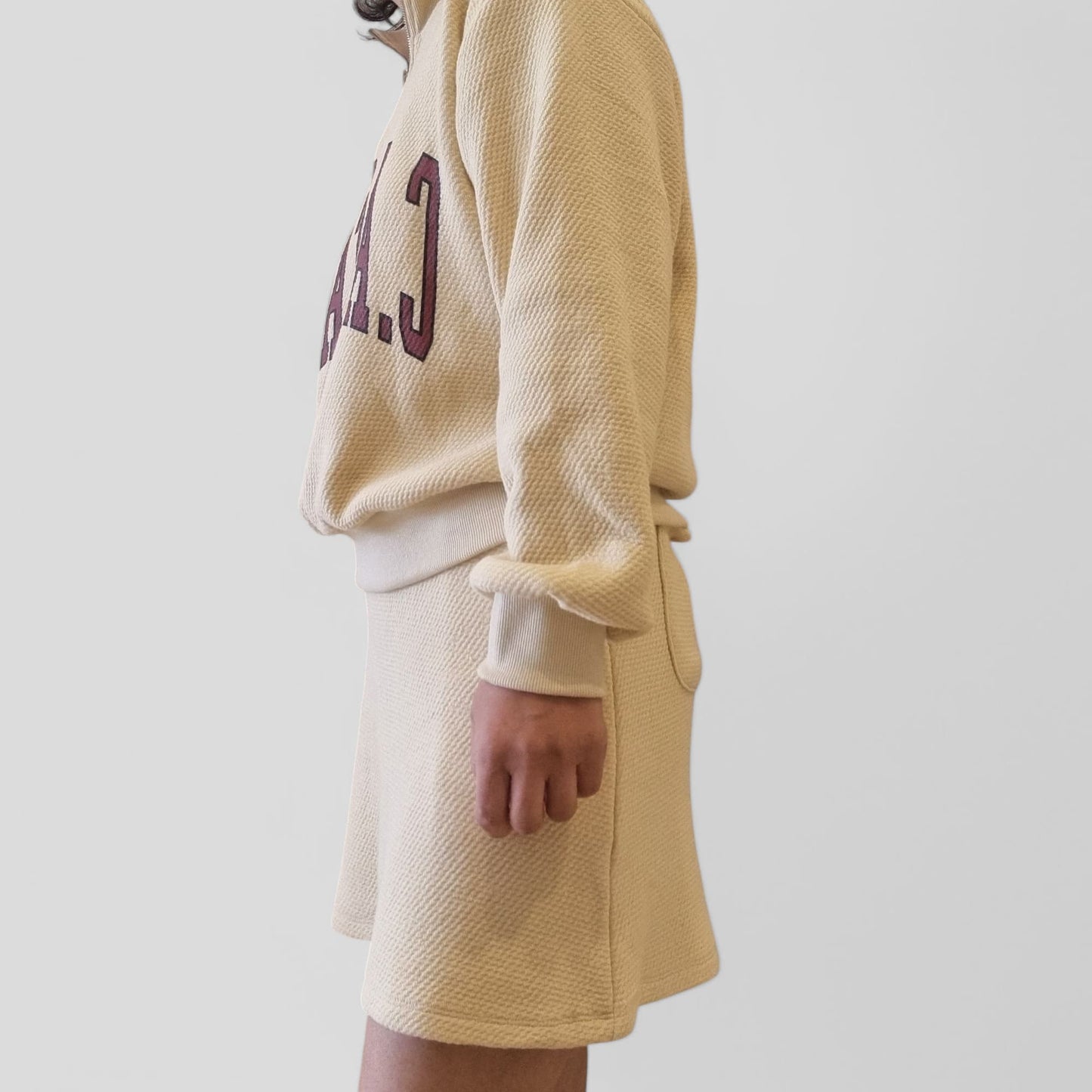 Model wearing beige zip-up sweatshirt – side profile view