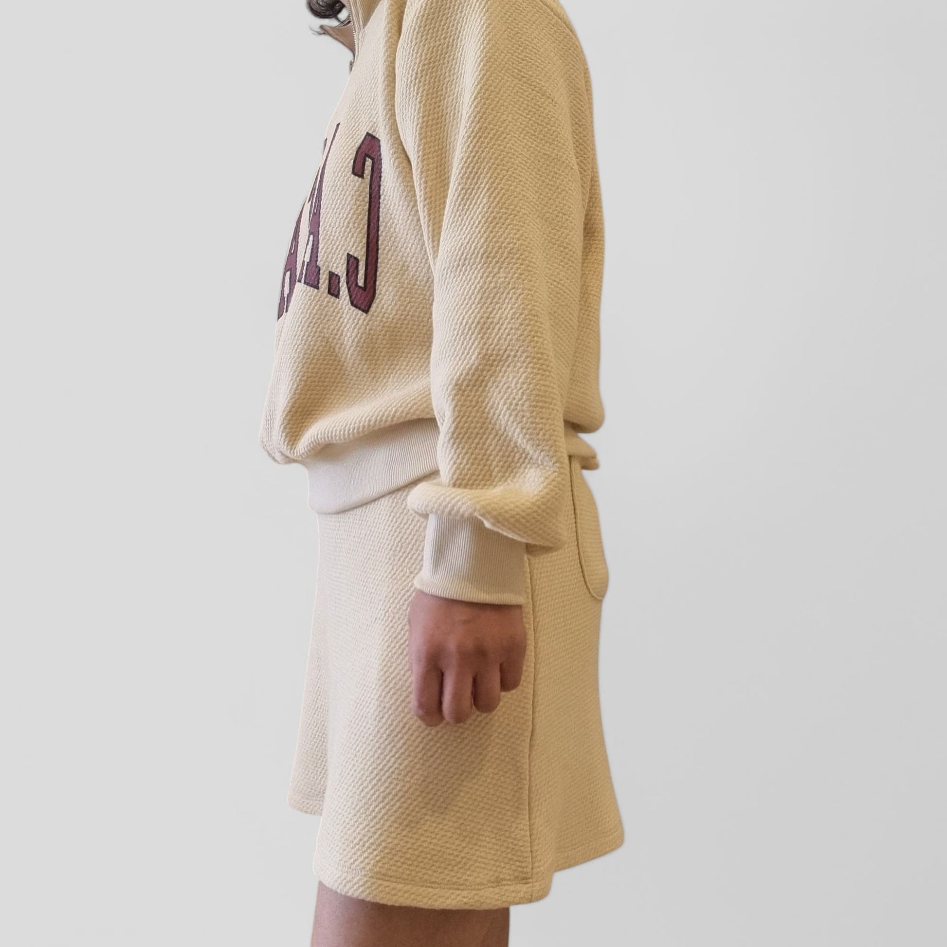 Model wearing beige zip-up sweatshirt – side profile view