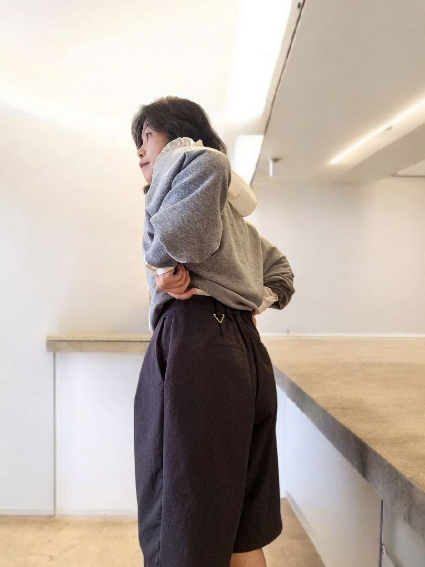 Side view of model wearing dark wide-leg pants with a grey hoodie