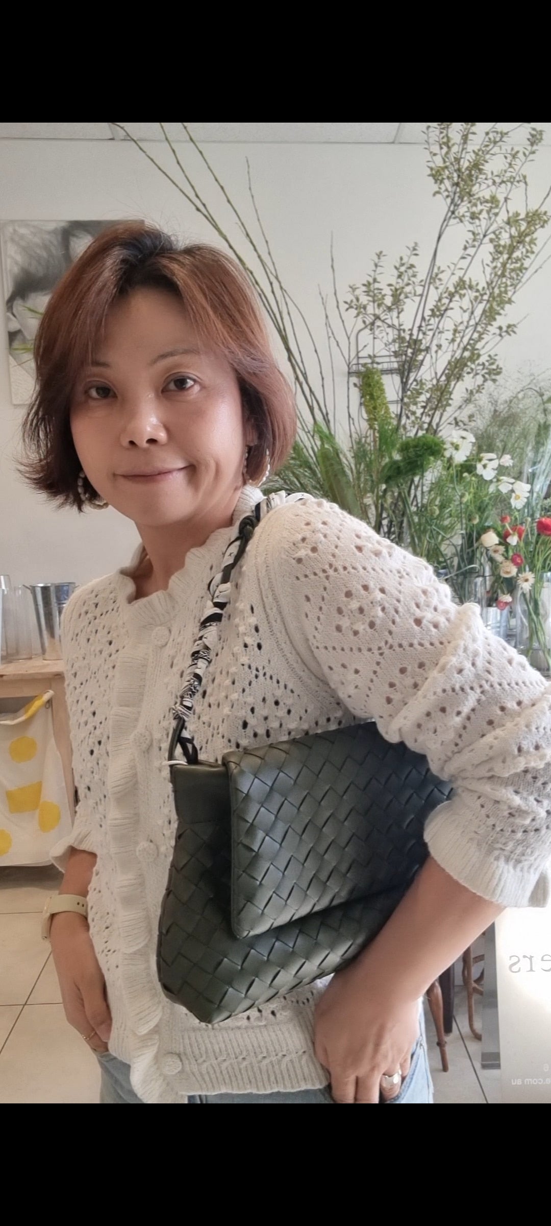 Woman styling cream ruffle cardigan in natural light lifestyle shot