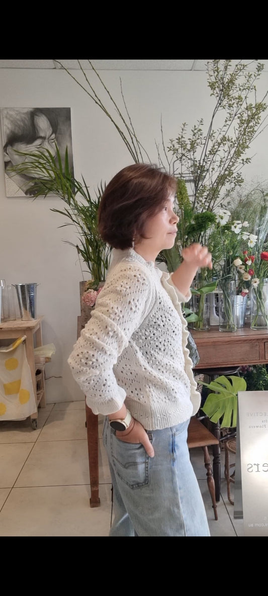Woman wearing cream alpaca ruffle cardigan styled with casual outfit indoor