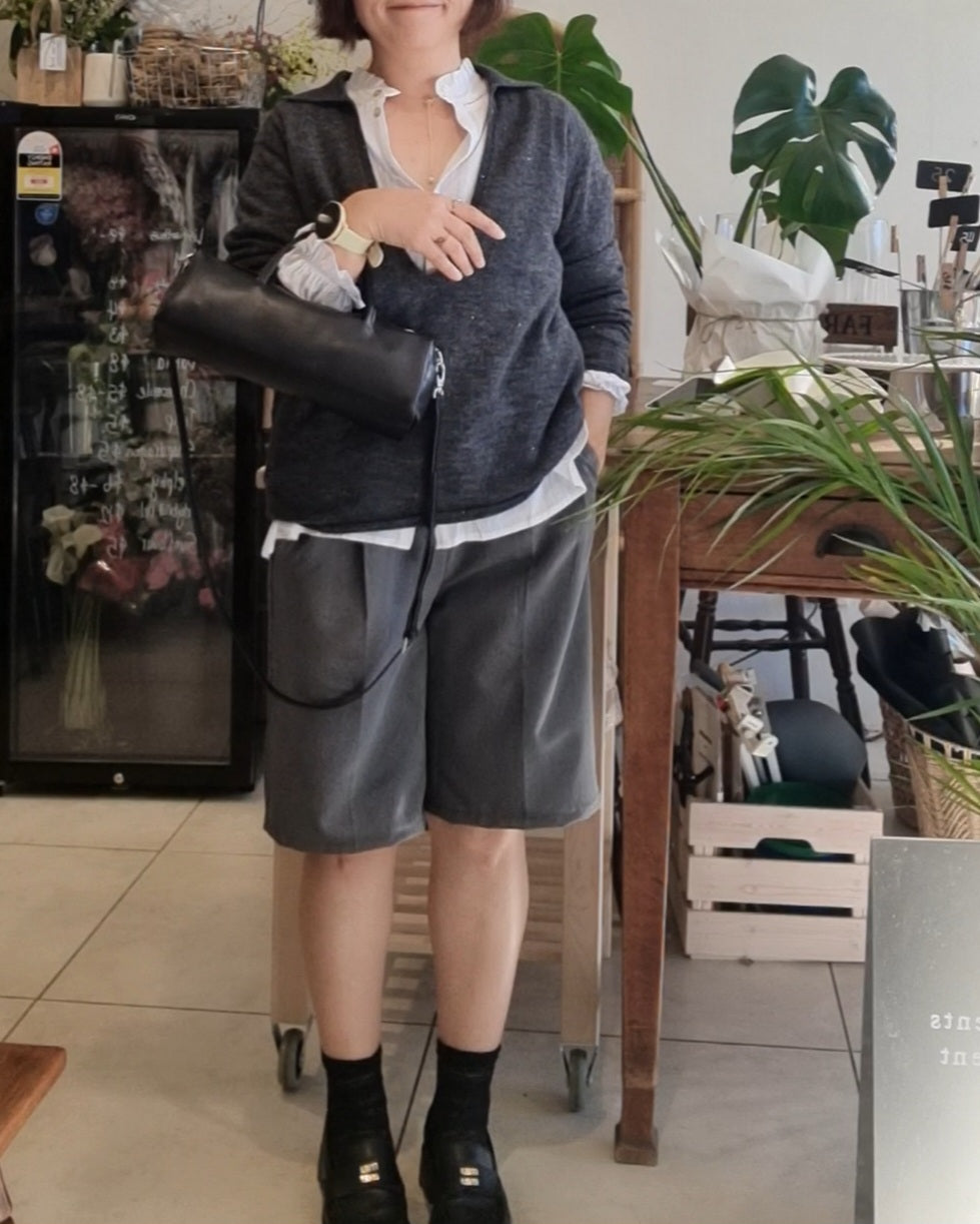 Model wearing a dark grey wool blend knit top with grey pants, styled with a black leather bag