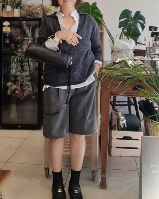 Model wearing a dark grey wool blend knit top with grey pants, styled with a black leather bag