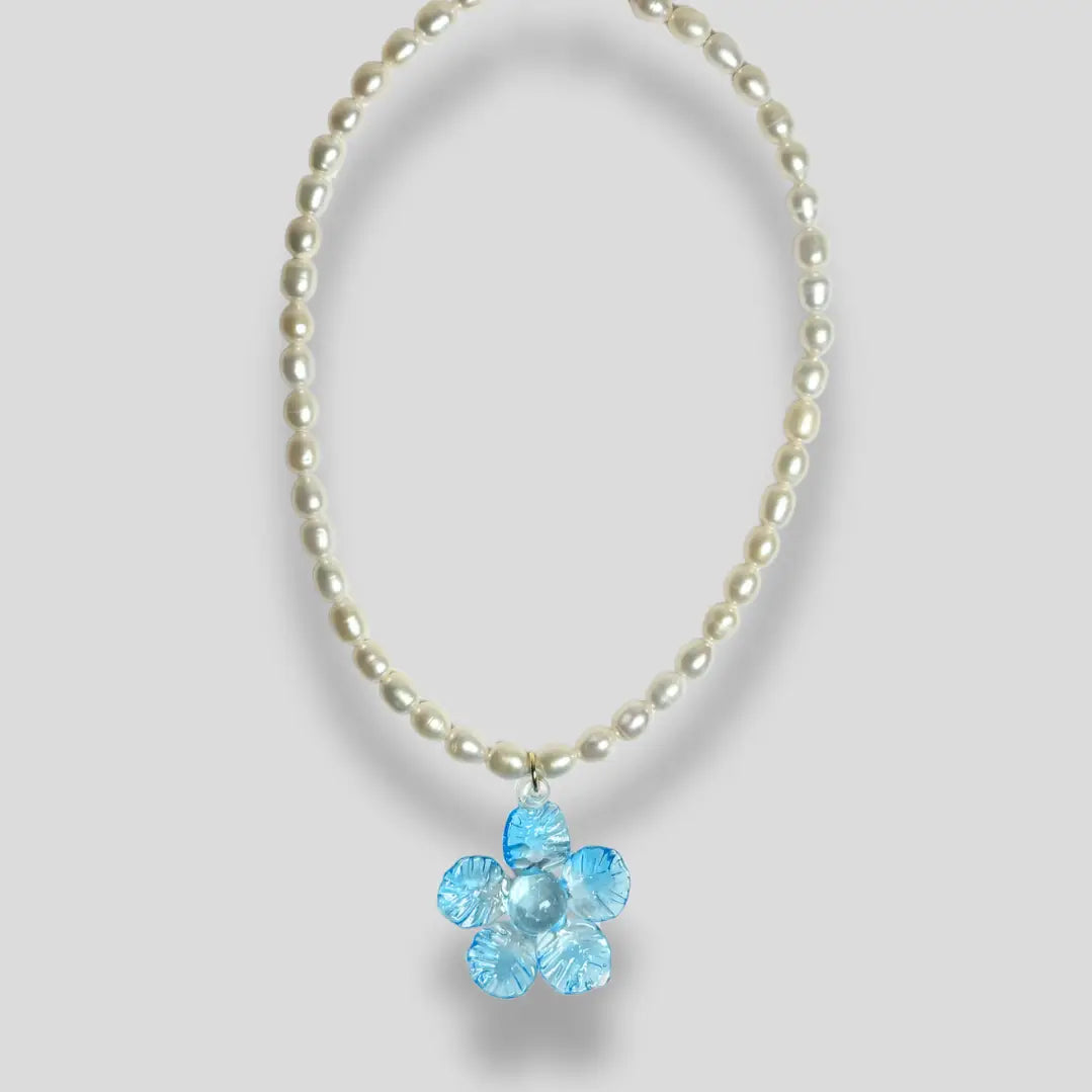 Pearl beaded necklace featuring a blue glass flower pendant, displayed on a light grey background.