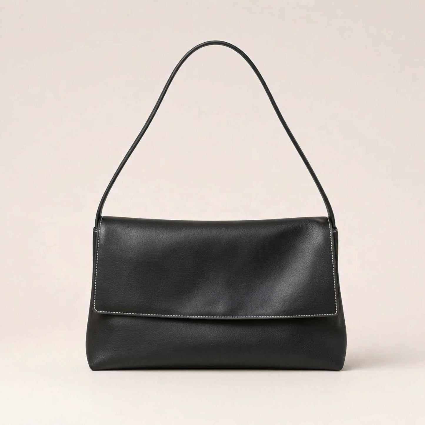 A black leather shoulder bag with a single thin strap and a flap closure, shown against a plain light beige background.