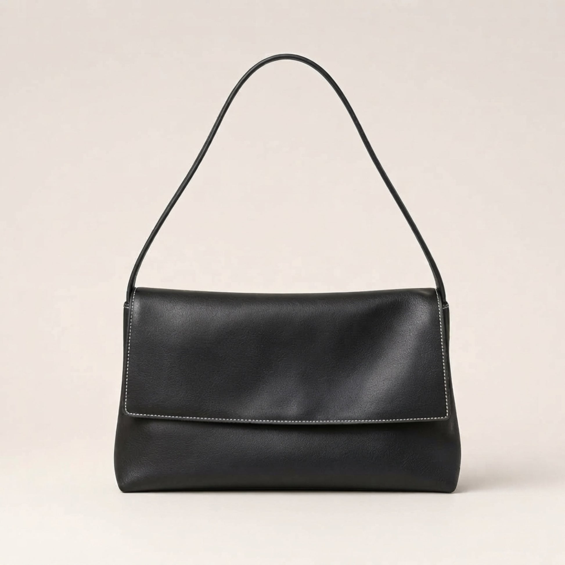 A black leather shoulder bag with a single thin strap and a flap closure, shown against a plain light beige background.