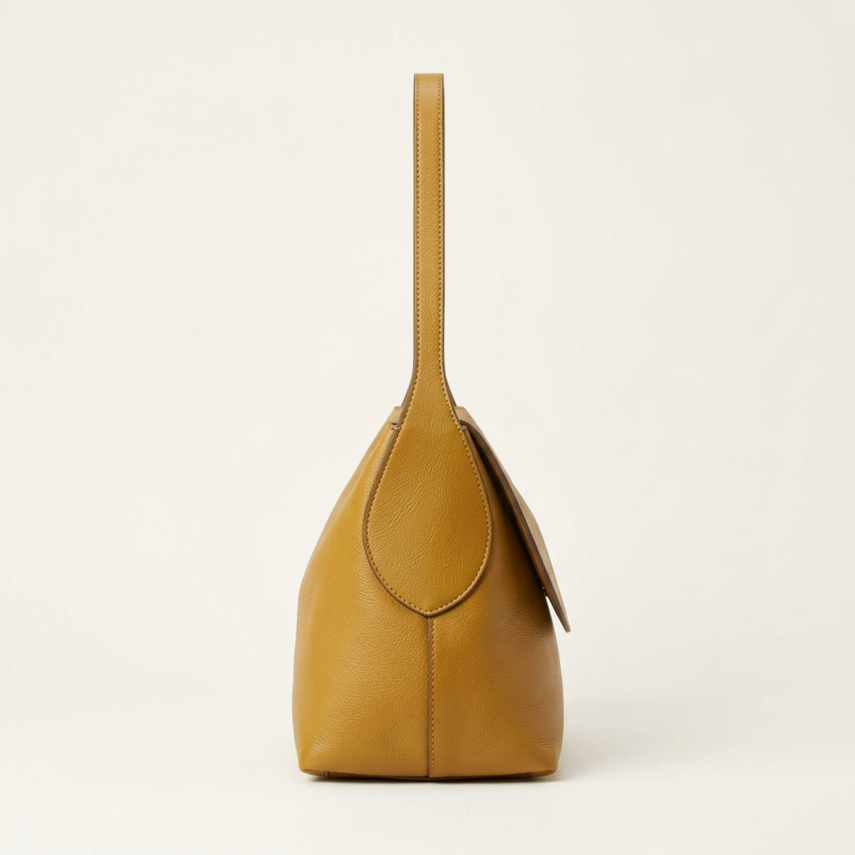 A mustard yellow pebbled leather shoulder bag with a single top handle, shown from the back against a clean, off-white background.