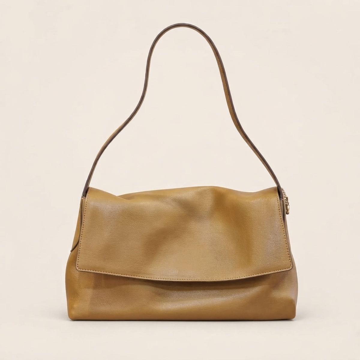 A tan leather shoulder bag with a single strap and a front flap, photographed against a plain light beige background.