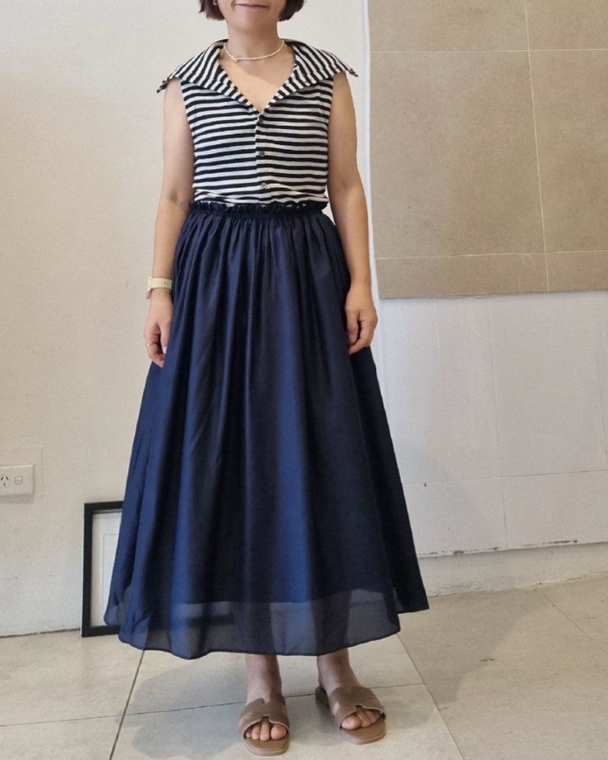 Model wearing a navy silk and cotton skirt dress with elastic waist, styled with a black and white striped sleeveless top, shown on a 160cm model wearing size 10.
