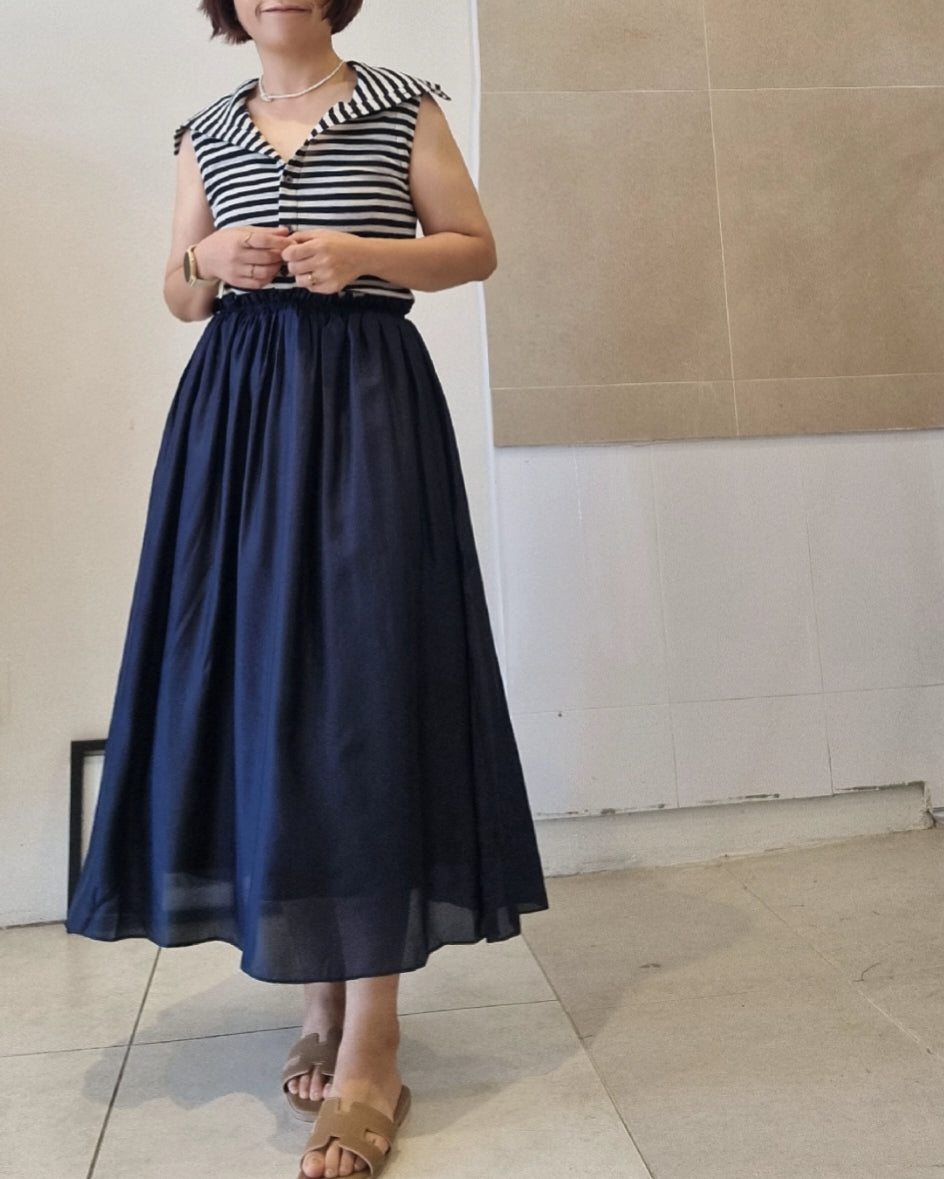 Model wearing a navy silk midi skirt dress with elastic waist and striped sleeveless top, styled for everyday elegance