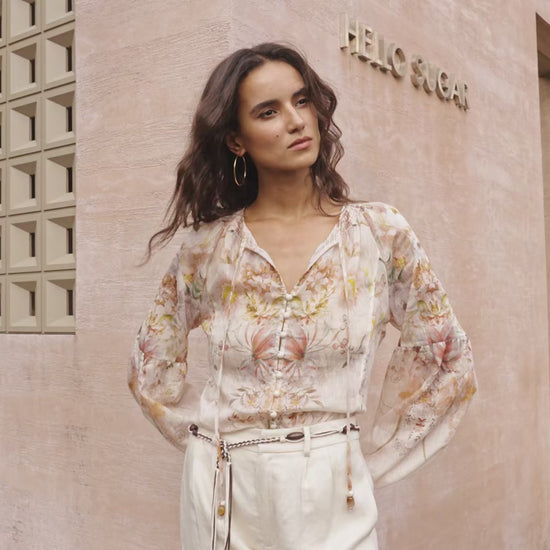 “Model wearing a floral blouse in soft neutral tones — showcasing the romantic print, lightweight fabric movement, and relaxed feminine silhouette. Flowy floral top styling, elegant everyday wear, Korean fashion inspired blouse.”