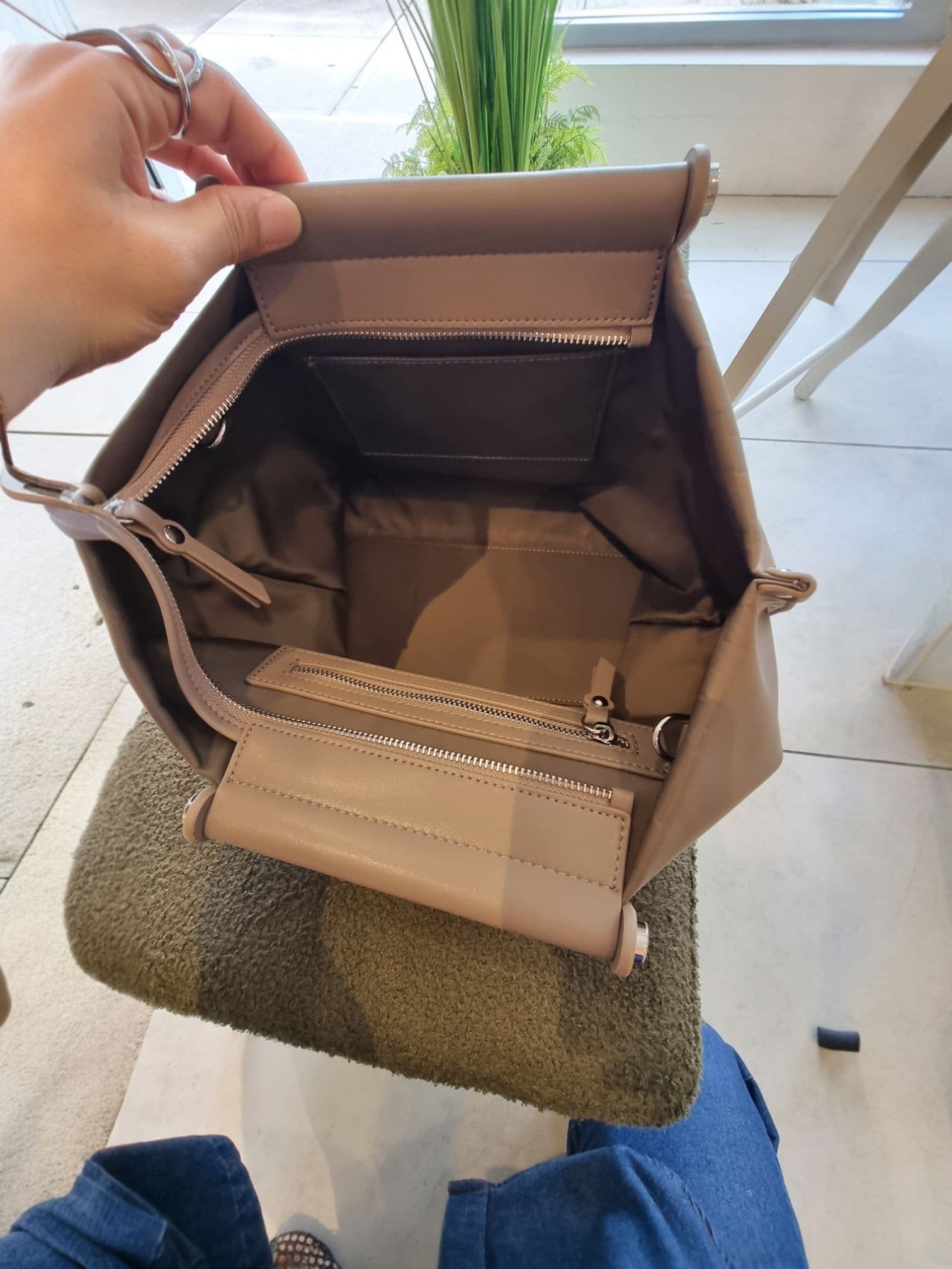 Hand opening the EB brown bag to show inside capacity.