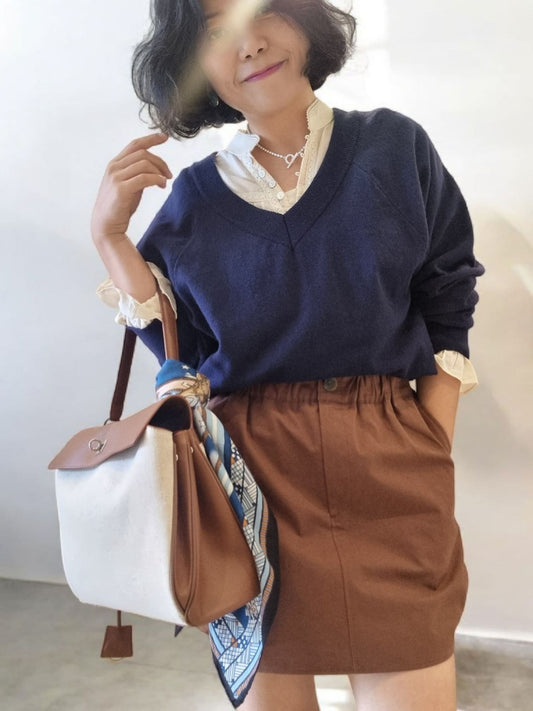 Model wearing brown pumpkin skirt with navy sweater, front view.