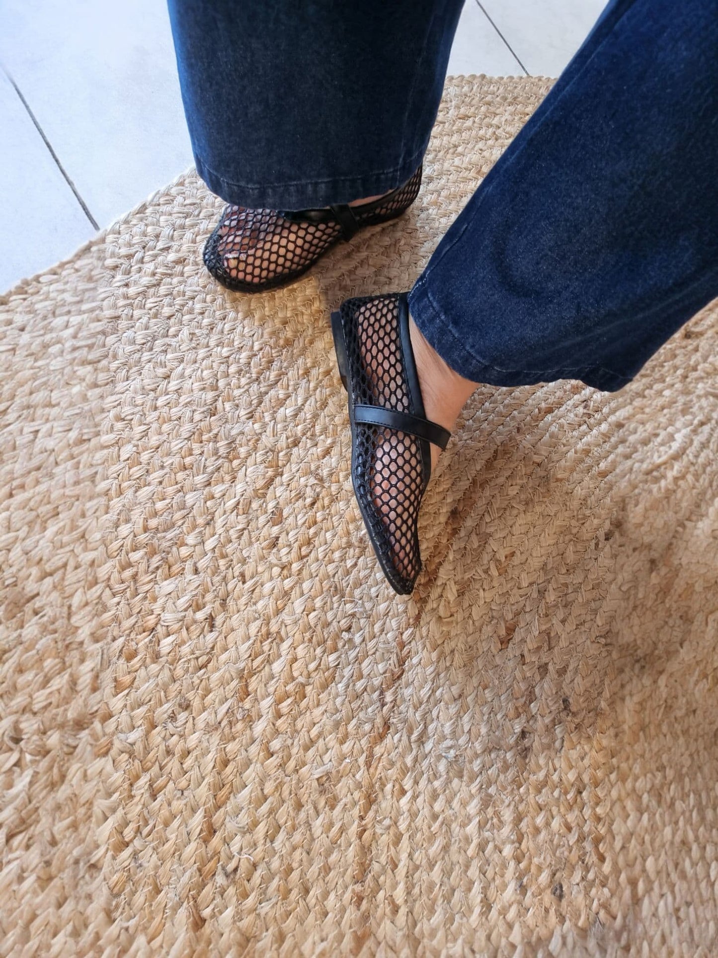 Close-up of black mesh Mary Jane flats on beige rug
