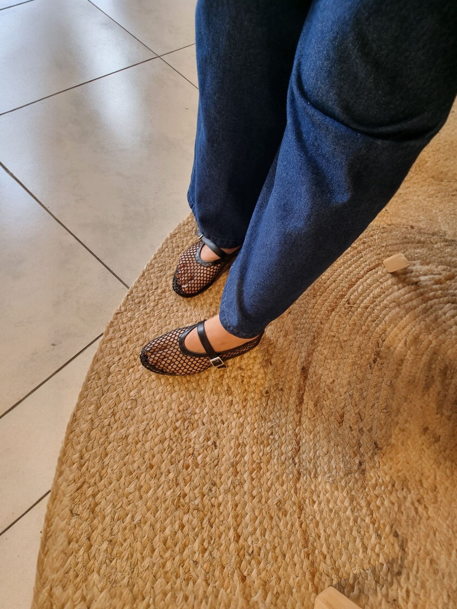 Top-down view of black mesh Mary Jane flats being tried on