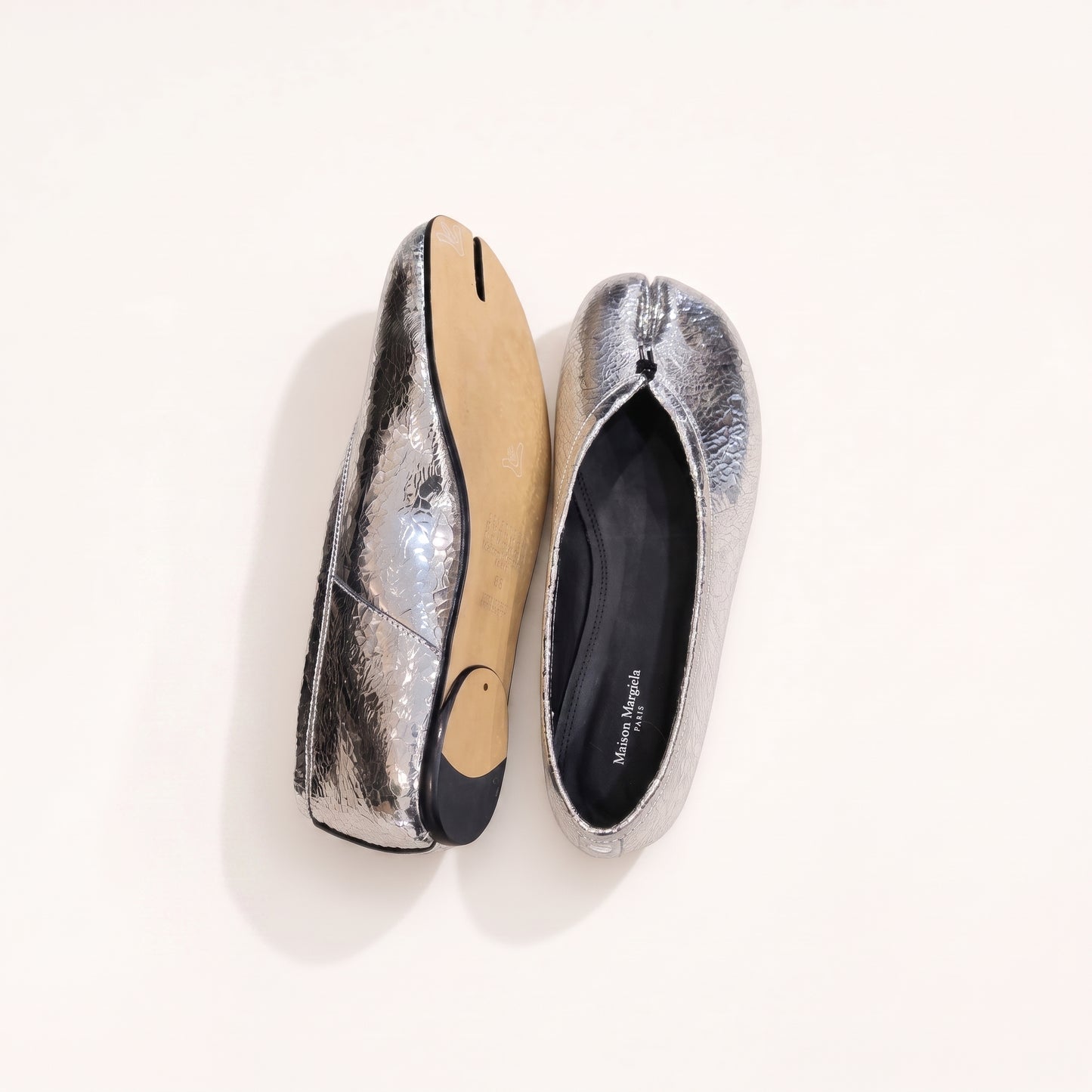 A pair of metallic silver flat shoes with a textured, crinkled finish, shown from both the top and side angles on a clean off-white background. The brand name 'Kreations Kreations Paris' is visible on the black insole lining.