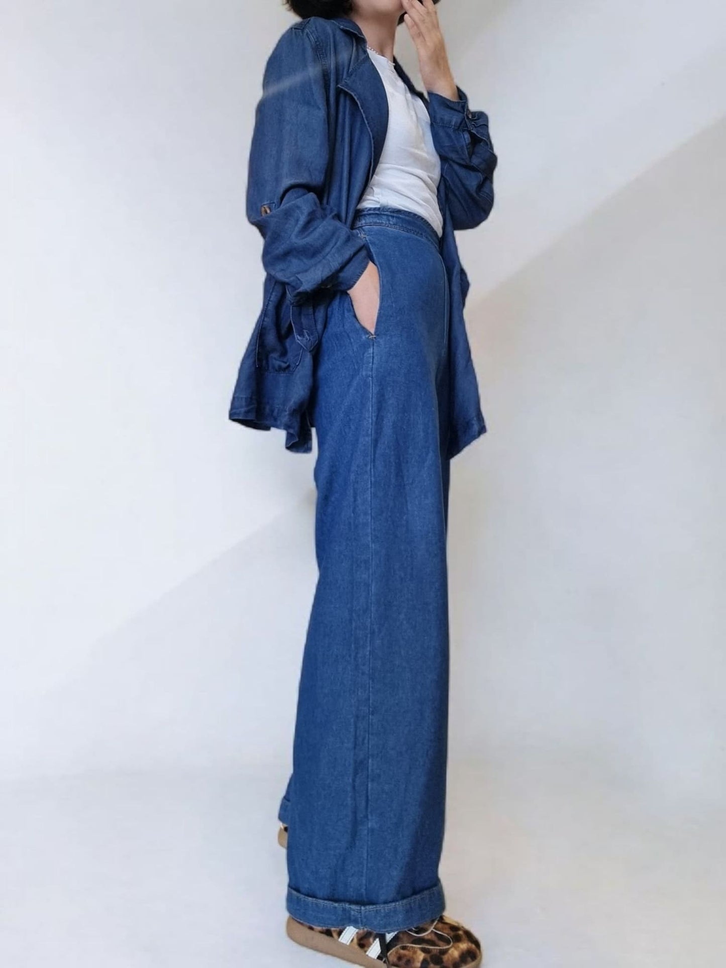 “Side view of loose-fit blue cotton jacket showing roll-up sleeve detail.”