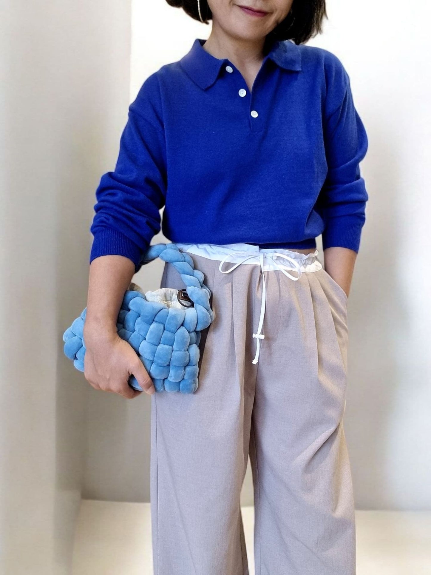 “Blue cotton top paired with beige pants and handbag”