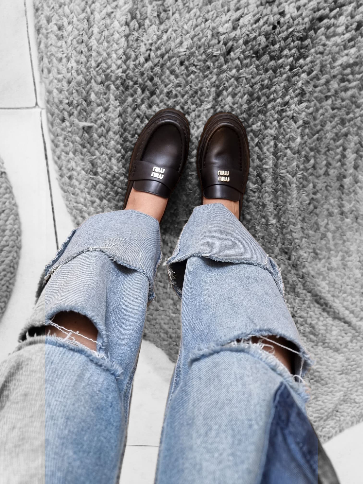 “Woman wearing black leather loafers with jeans for a casual outfit.”