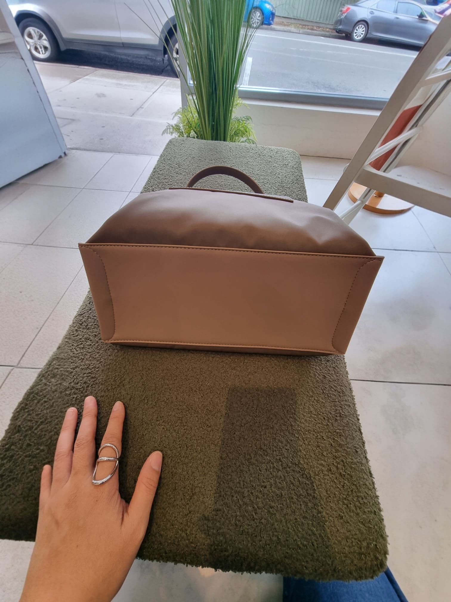 Hand reaching toward brown EB bag inside the store.