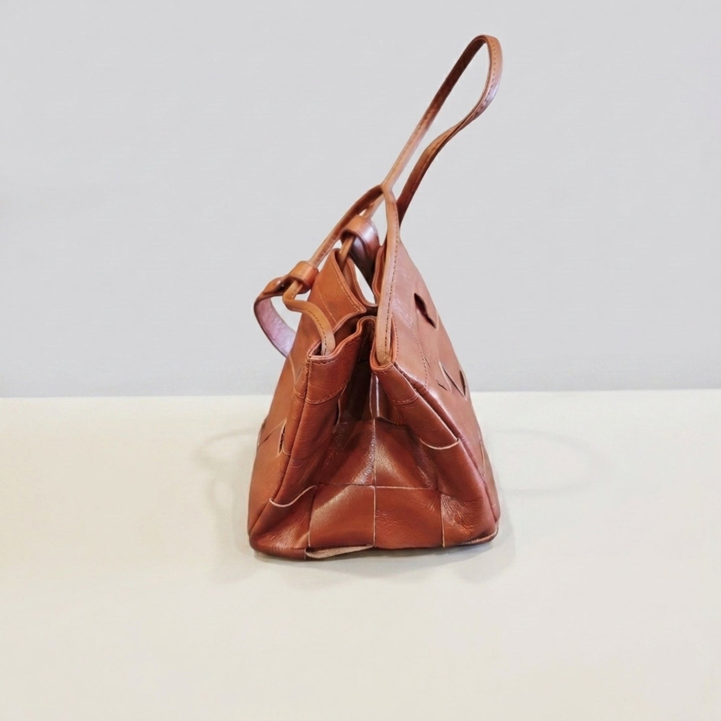 Side view of brown woven genuine leather crossbody bag
