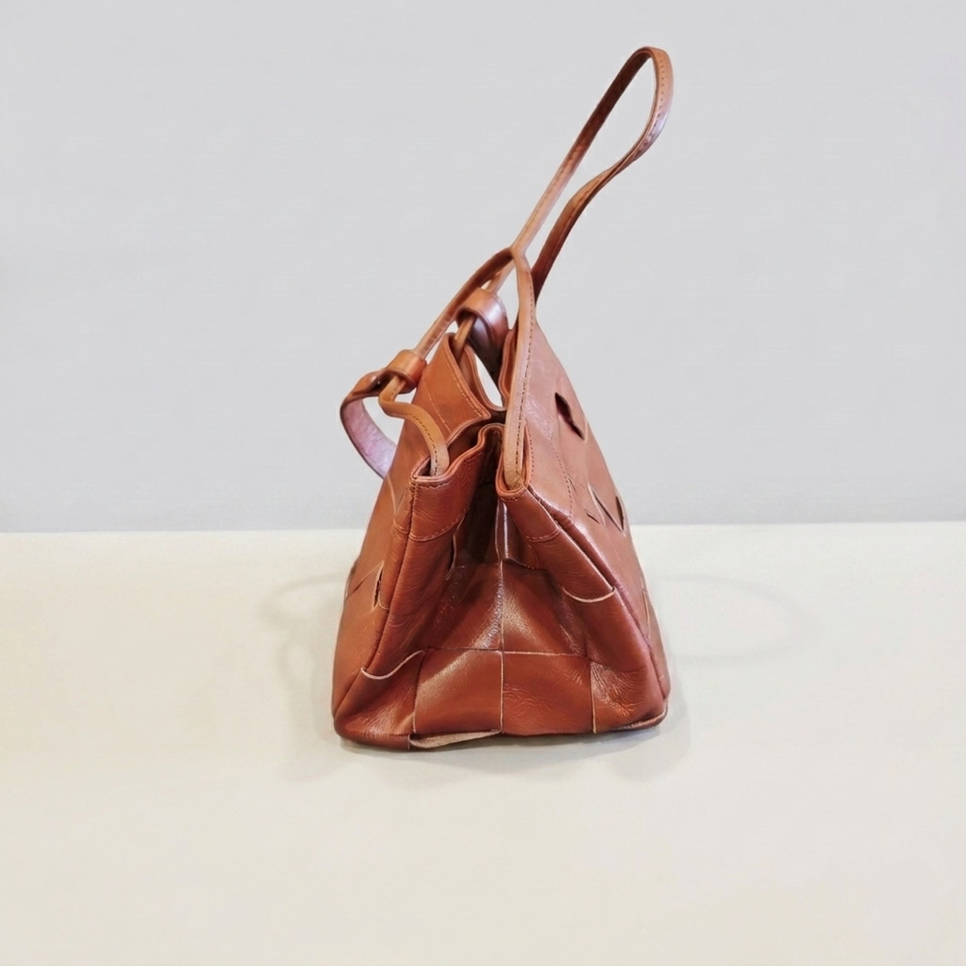 Side view of brown woven genuine leather crossbody bag