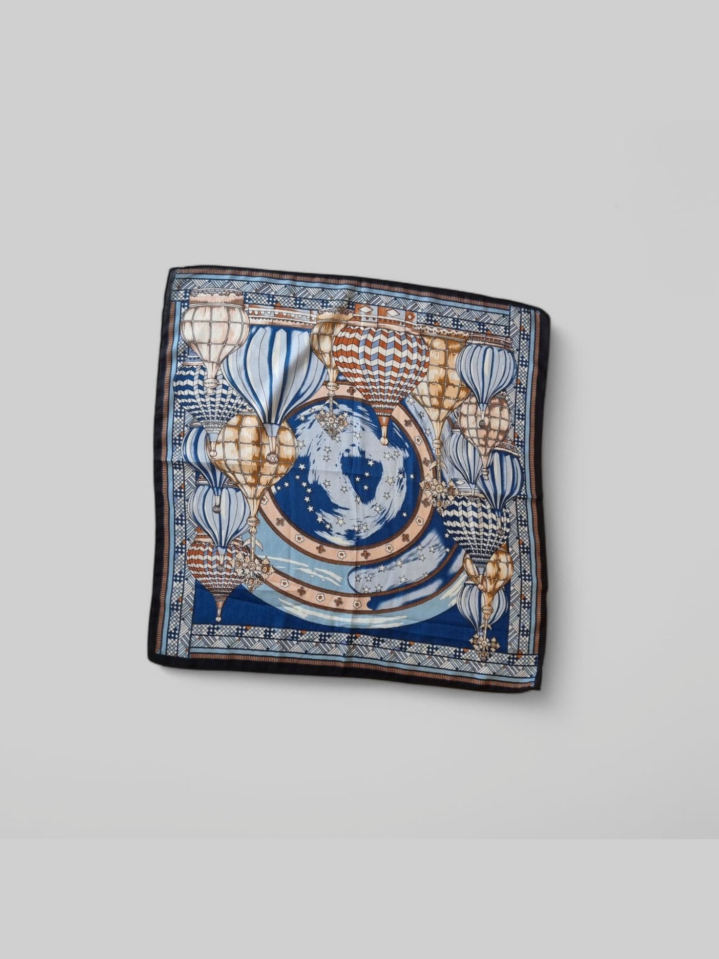 “Blue patterned square scarf displayed neatly flat.”