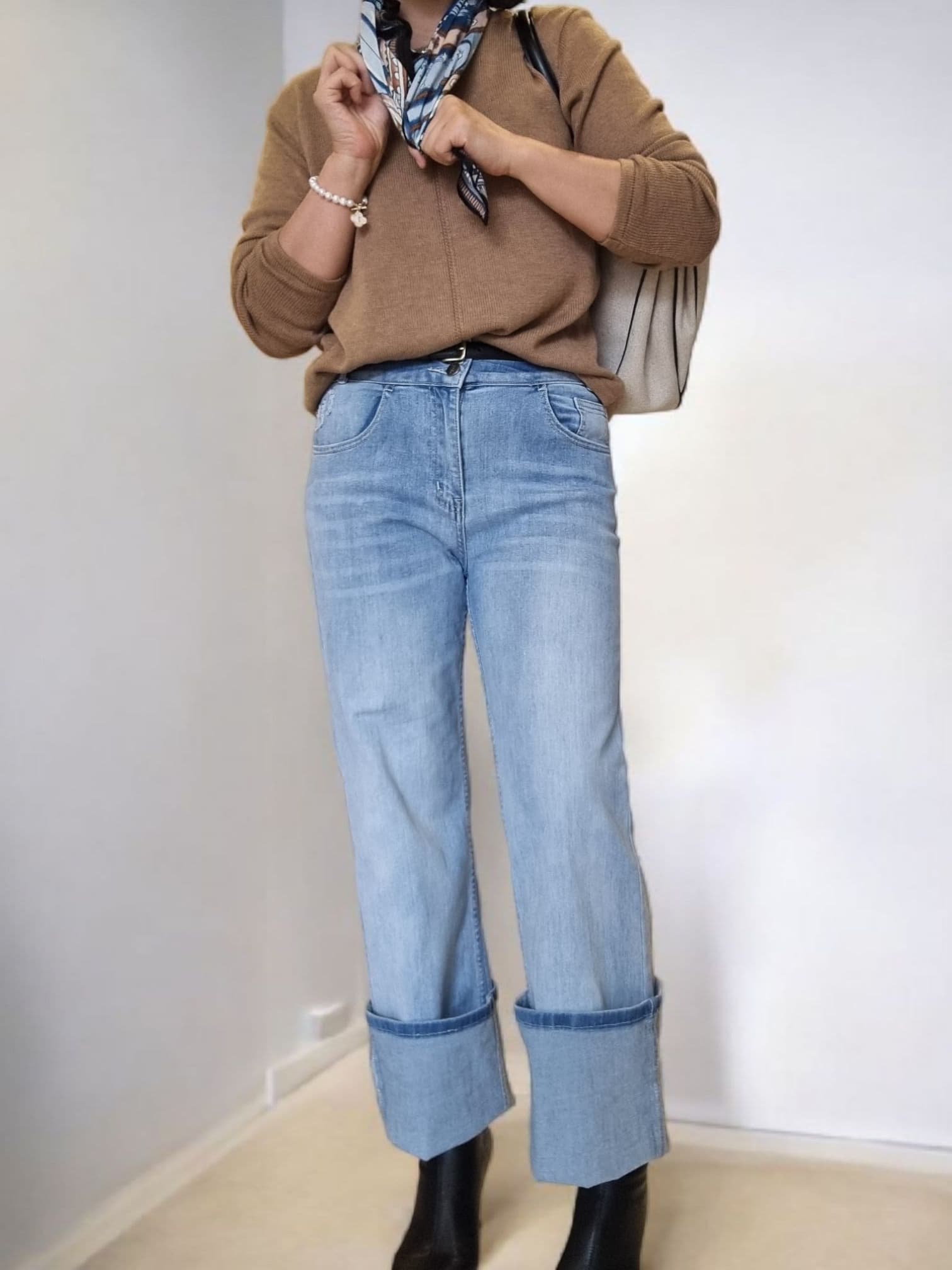 “Blue patterned scarf worn around the neck with casual denim outfit.”